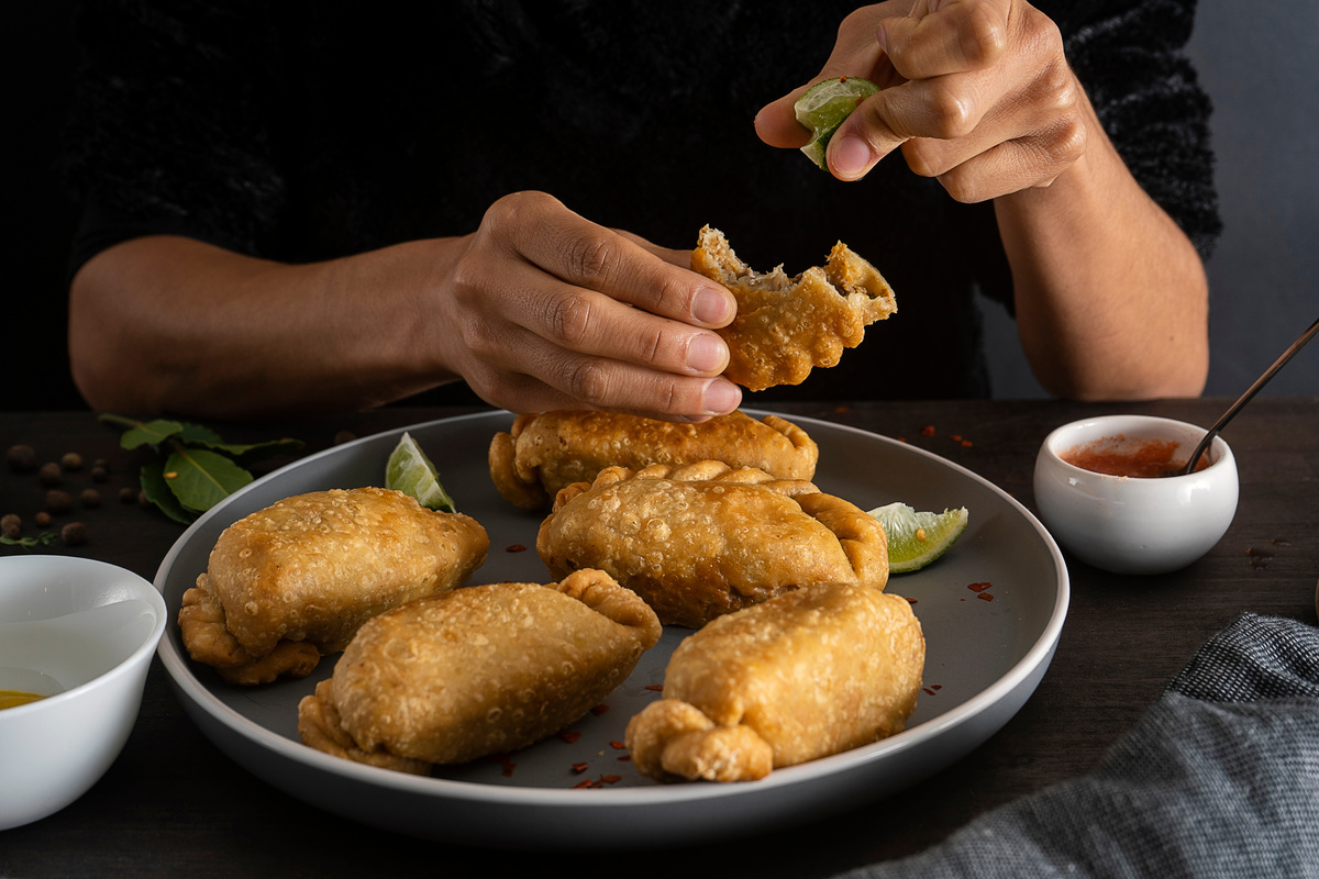 Man Squeezing Lime into the Fried Empanadas